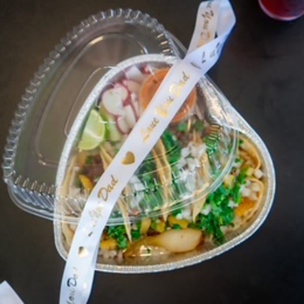 Taco Riendo Taqueria's tacos in a heart-shaped container with a "Love You Dad" ribbon.