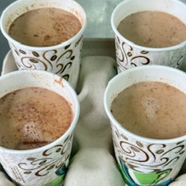 Four cups of Mexican hot chocolate with cinnamon, in a cardboard carrier.