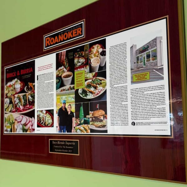 A framed magazine article about Taco Riendo Taqueria, featuring food photos and restaurant owners.