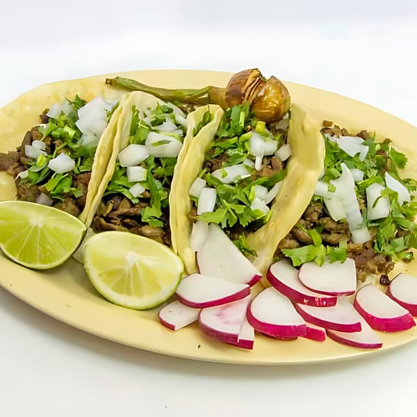 Three carne asada tacos with cilantro, onions, lime wedges, and sliced radishes on a yellow plate.